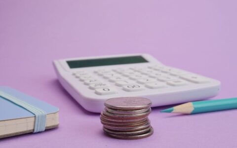 Calculator, coins, and stationery symbolize budgeting and finance on a pastel purple backdrop.