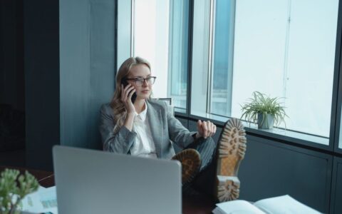Professional woman in office setting, relaxed yet focused, making a call.