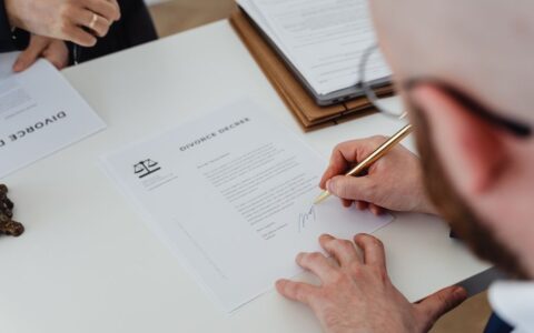 Close-up of a person signing a divorce decree on a desk.