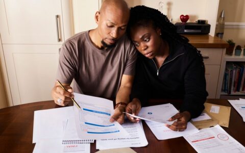 A couple sitting at a table reviewing financial documents, highlighting domestic budgeting.