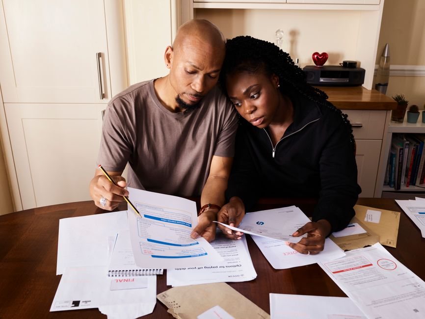 A couple sitting at a table reviewing financial documents, highlighting domestic budgeting.