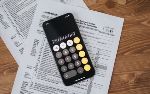 Overhead view of smartphone calculator on tax forms for finance and accounting.